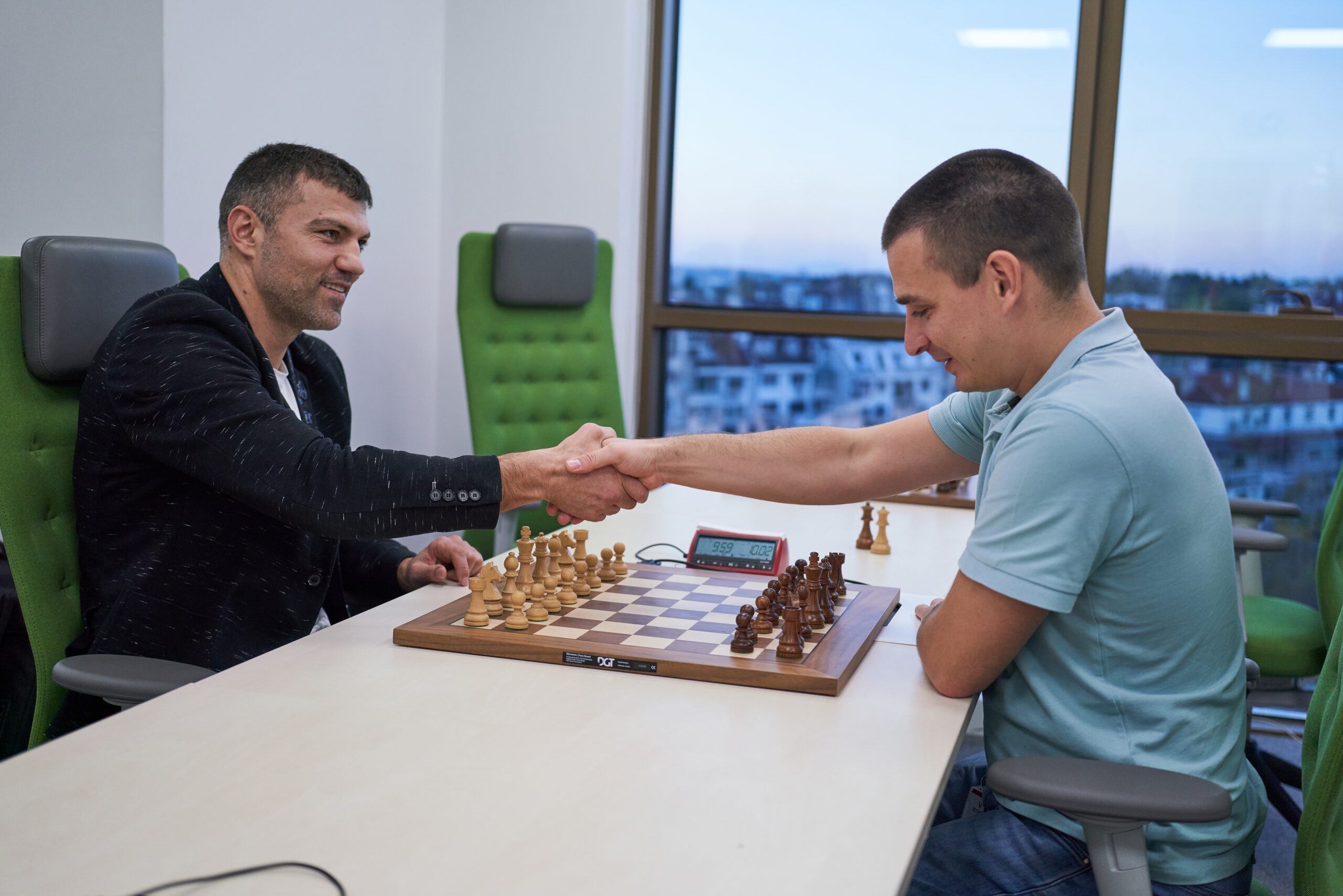 Two men shaking hands over a chess board.
